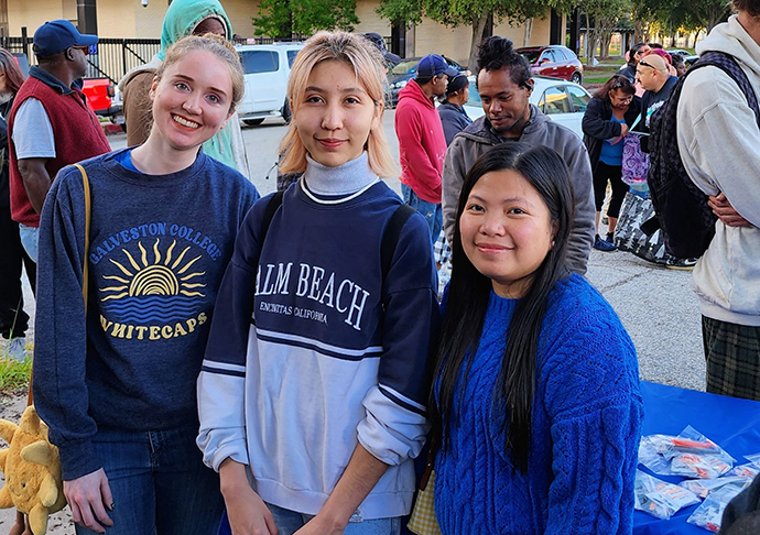 Three Galveston College Students stand outside at breakfast event for the community.