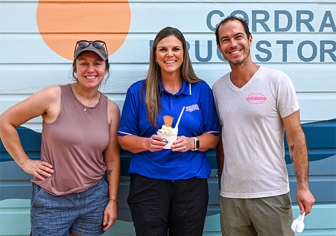 Three people stand together, one is holding a bowl of ice cream