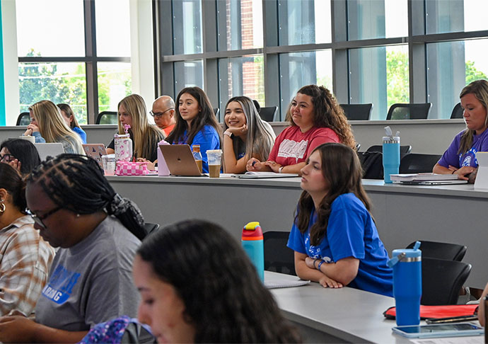 Students in a class look to front of lecture hall