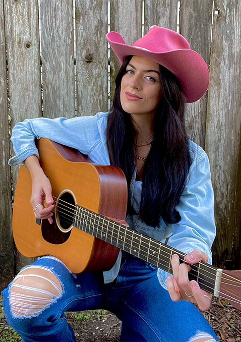 Person in pink cowboy holding guitar