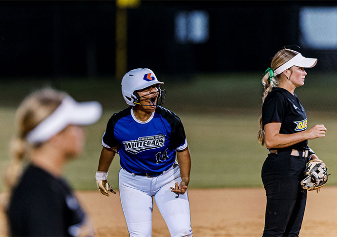 Softball player cheers team on after getting on base