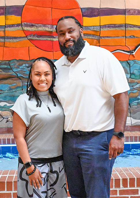 Couple stands together in front of sunset mural