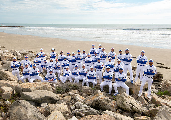 The 2025 Galveston College Whitecaps baseball team poses on the beach in Galveston.