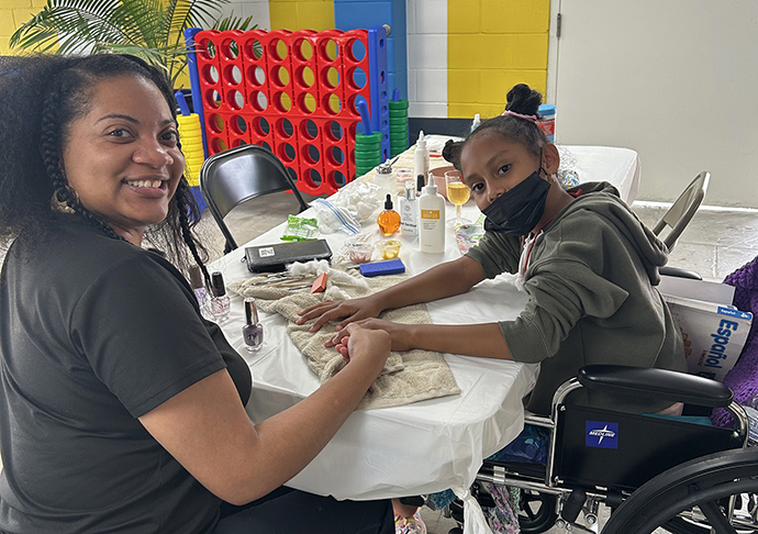 Woman gives young girl a manicure.